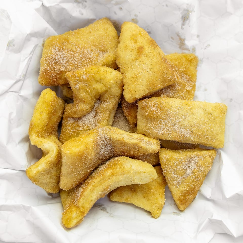 Mangiamo La Pizza's fried dough dessert, dusted with cinnamon sugar, served in white paper.