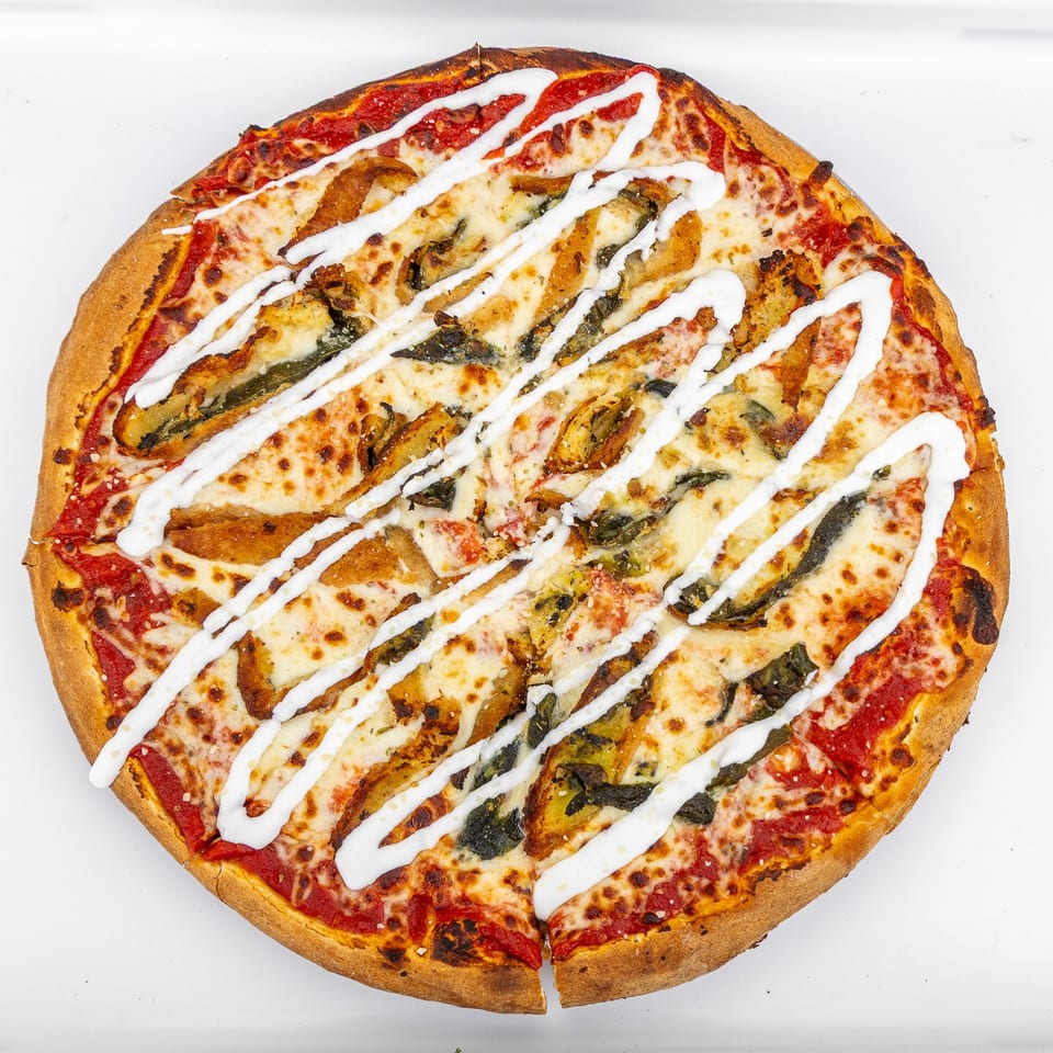 Mangiamo La Pizza's pizza with red sauce, cheese, green and brown toppings, and white sauce drizzle.